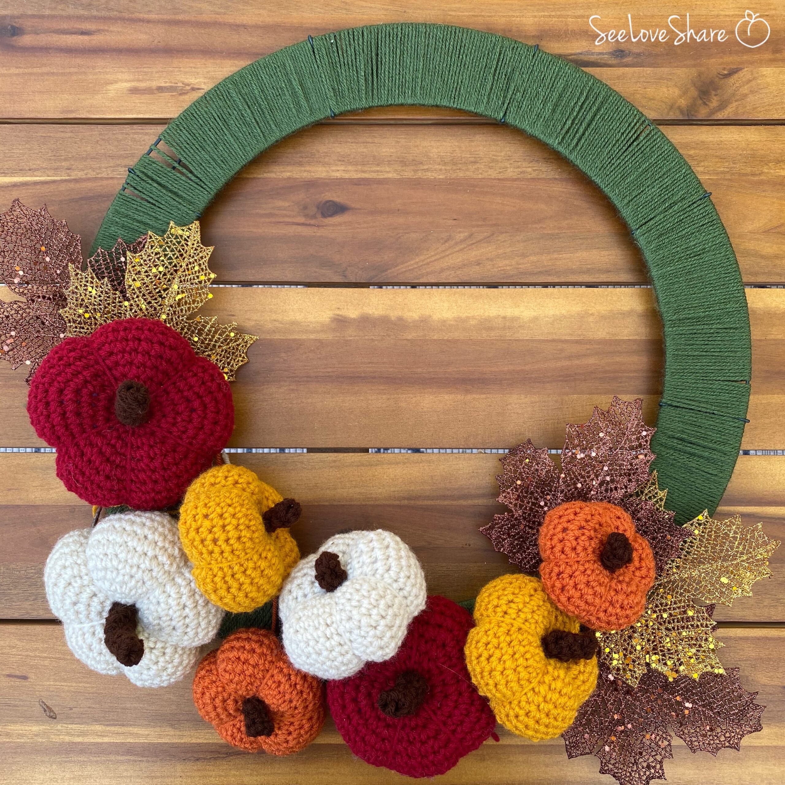 Hot glue gun attaching crochet pumpkins and decorative leaves to the wire wreath frame