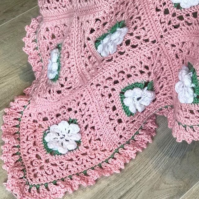 close-up of crochet flower granny square afghan showing pink white and green flower blossom detail