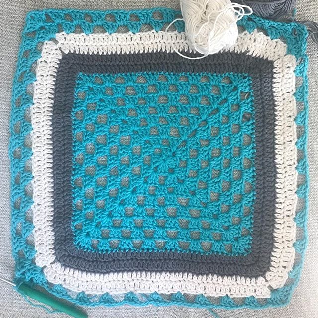 finished crochet granny square with marine blue gray and white colorblock rounds