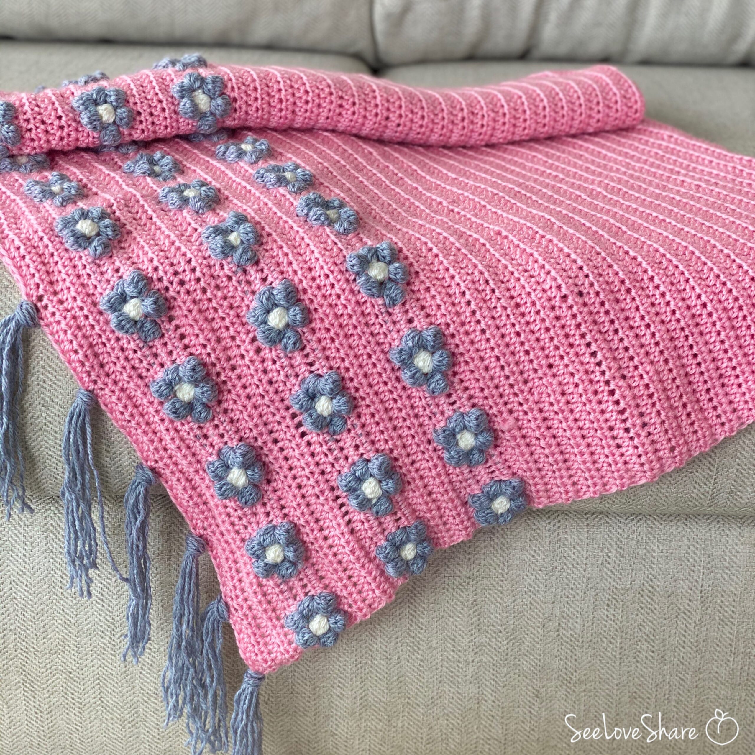 close-up of puff stitch flower border on pink crochet baby blanket