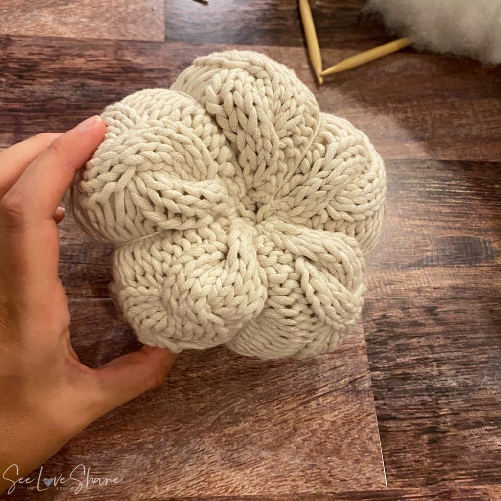 Wrapping yarn between the cables to crease the knit pumpkin