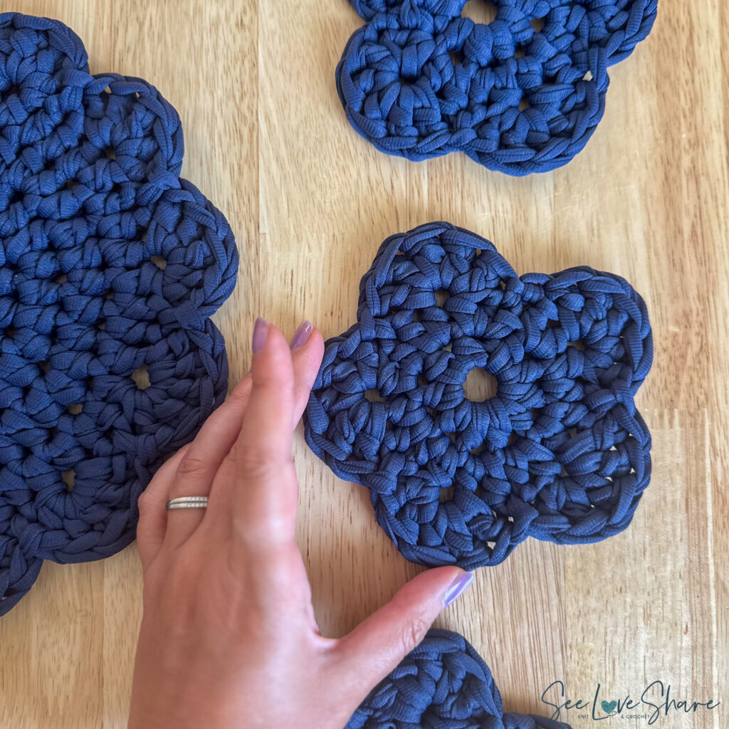 Free crochet flower coaster and trivet set pattern — navy chunky T-shirt yarn coasters and trivet styled with a white dutch oven and mug on a wood table.