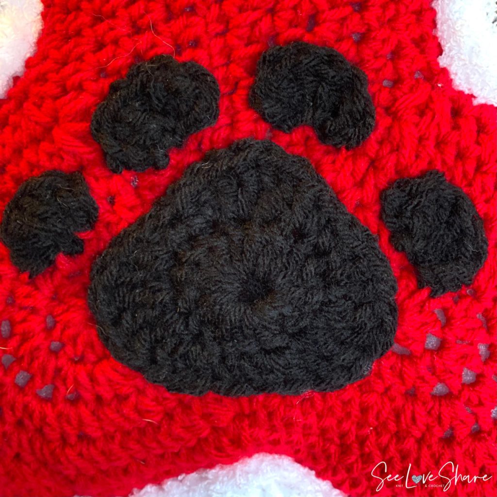 Free crochet dog paw pattern in black yarn — paw print motif applique for stockings, blankets, and pet-themed projects