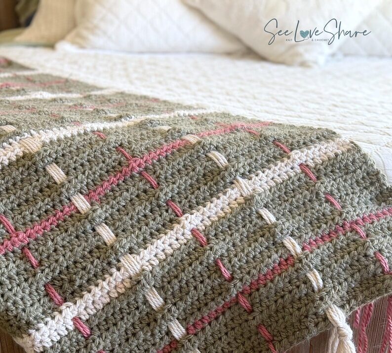 Woven tartan texture of the chunky plaid crochet blanket pattern with fringe, styled on a bed
