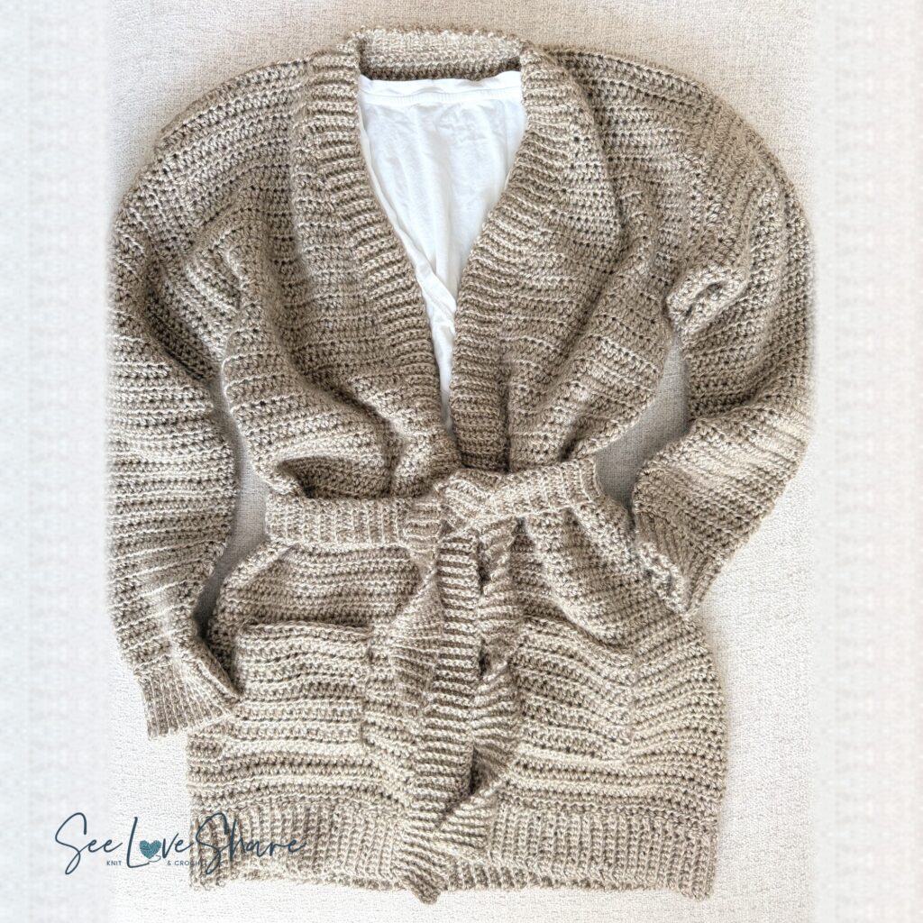 Flat lay of the finished seamless crochet cardigan in Lion Brand Heartland, with its tie belt